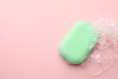 Photo of Soap bar with foam on light pink background, top view. Space for text