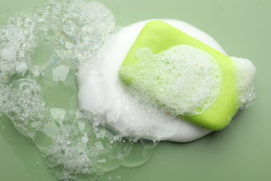 Photo of Soap bar with foam on green background