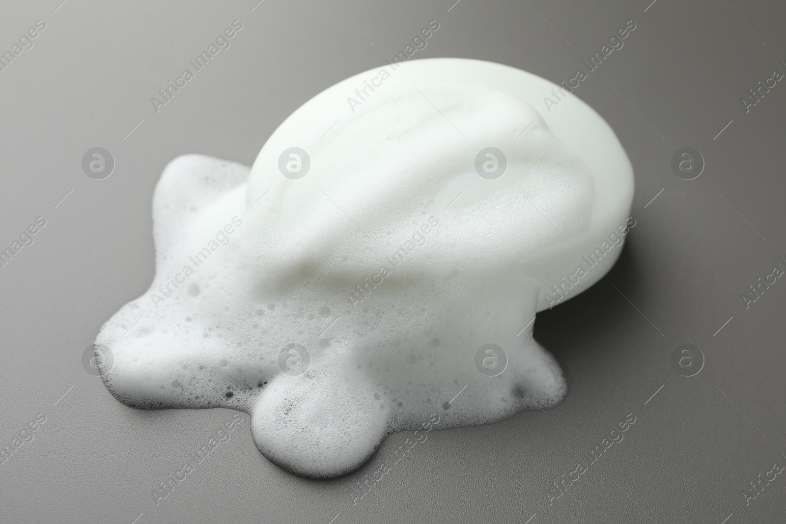 Photo of Soap bar with foam on grey background, closeup