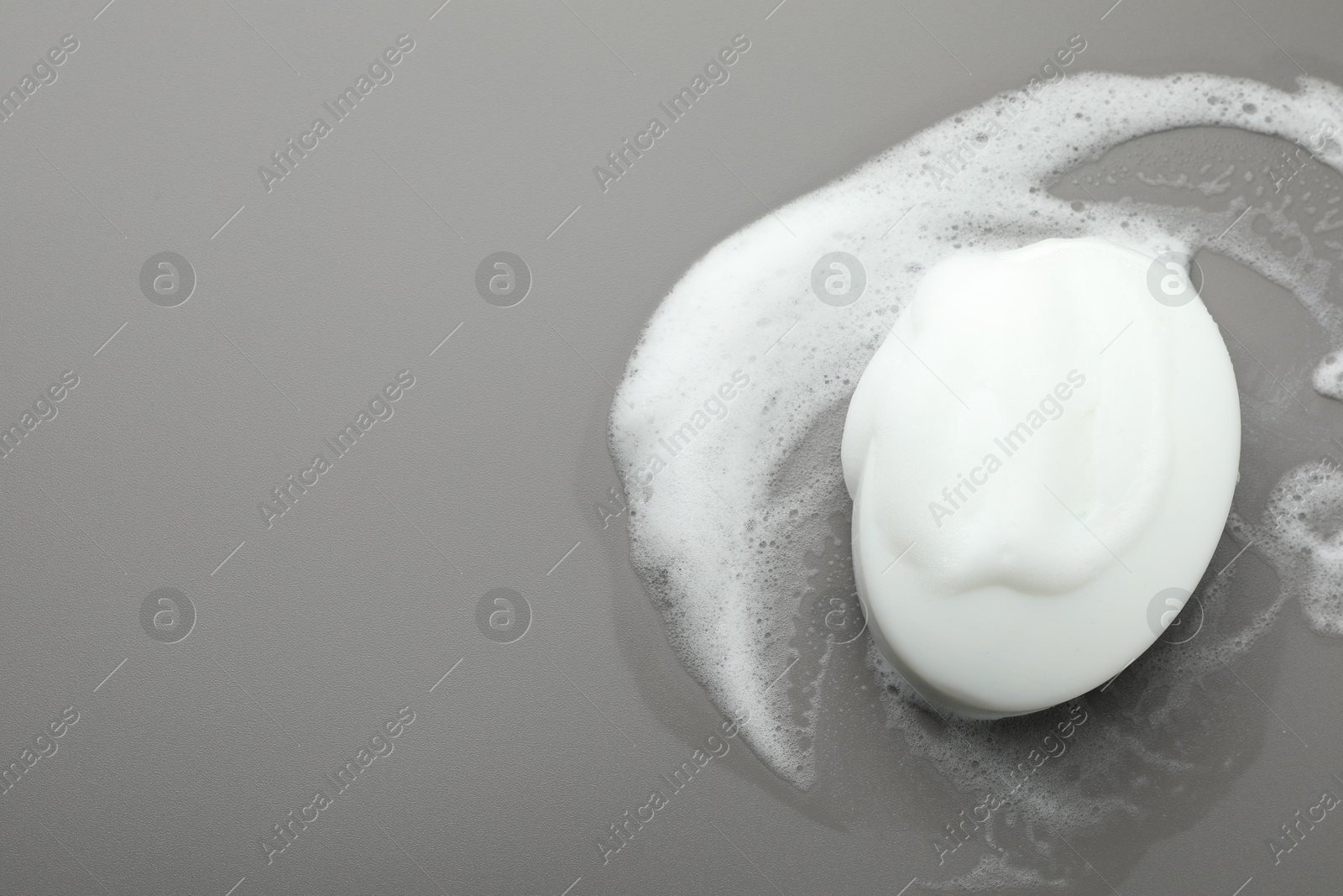 Photo of Soap bar with foam on grey background, top view. Space for text