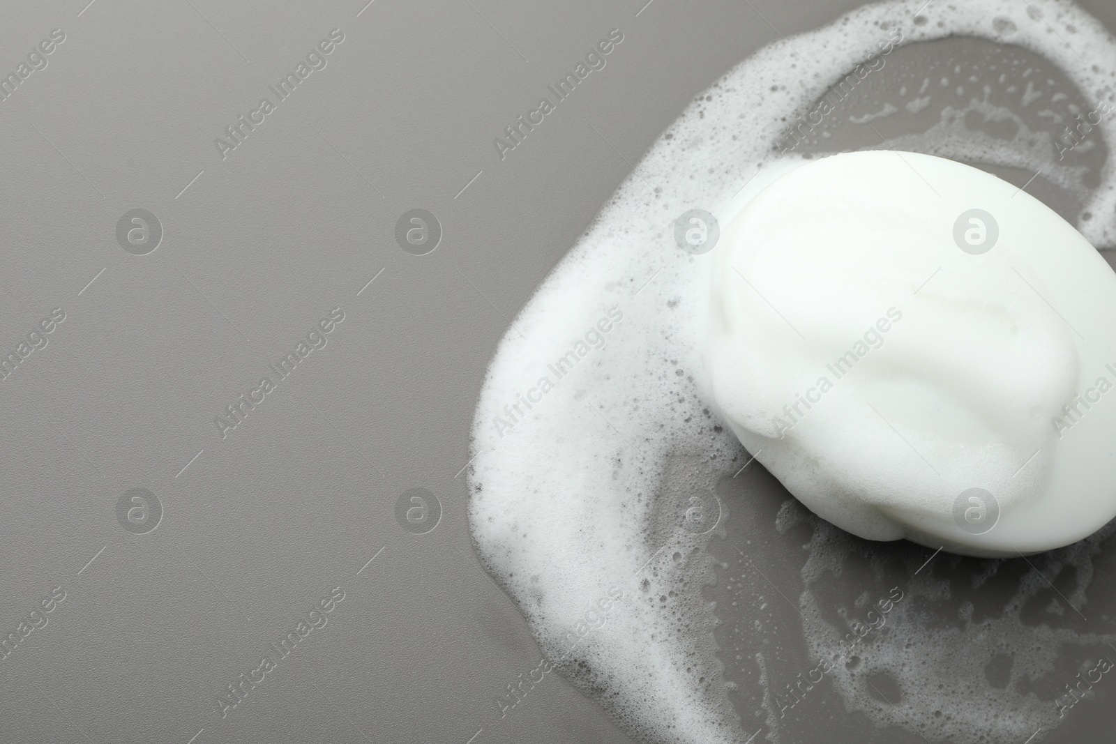 Photo of Soap bar with foam on grey background, top view. Space for text