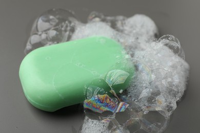 Photo of Soap bar with foam on grey background, closeup