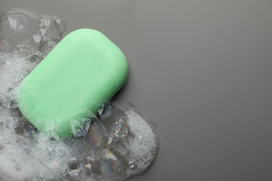 Photo of Soap bar with foam on grey background, top view. Space for text