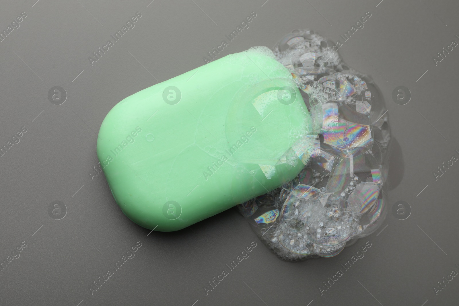 Photo of Soap bar with foam on grey background, top view