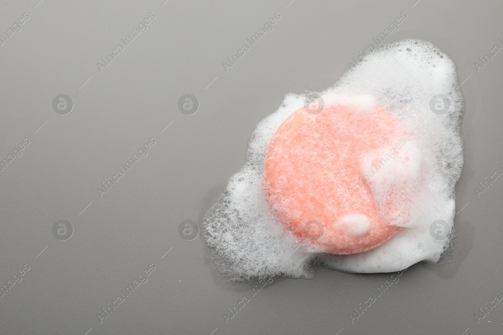 Photo of Soap bar with foam on grey background, top view. Space for text