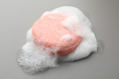 Photo of Soap bar with foam on grey background, closeup