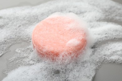 Photo of Soap bar with foam on grey background, closeup