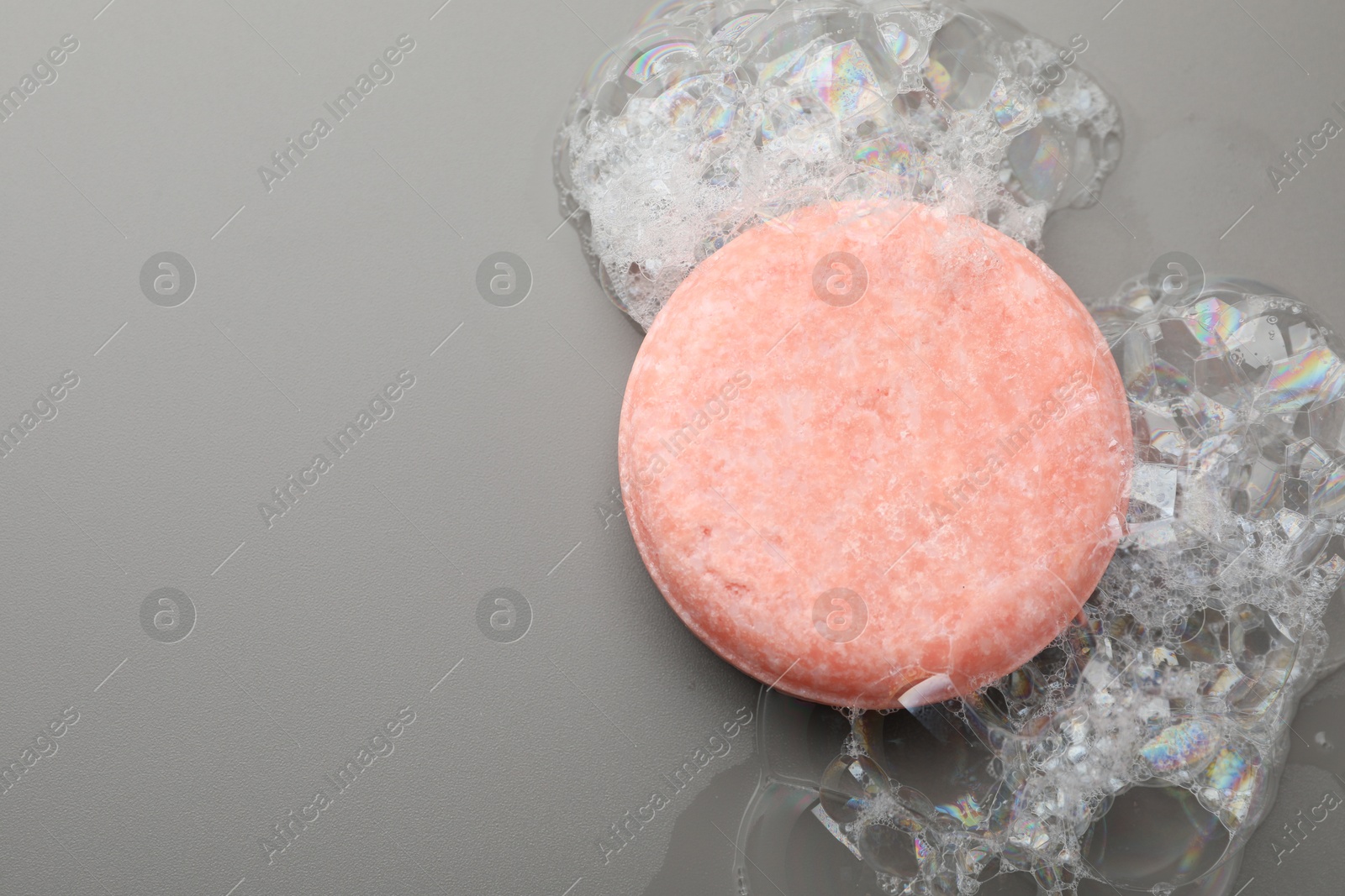 Photo of Soap bar with foam on grey background, top view. Space for text