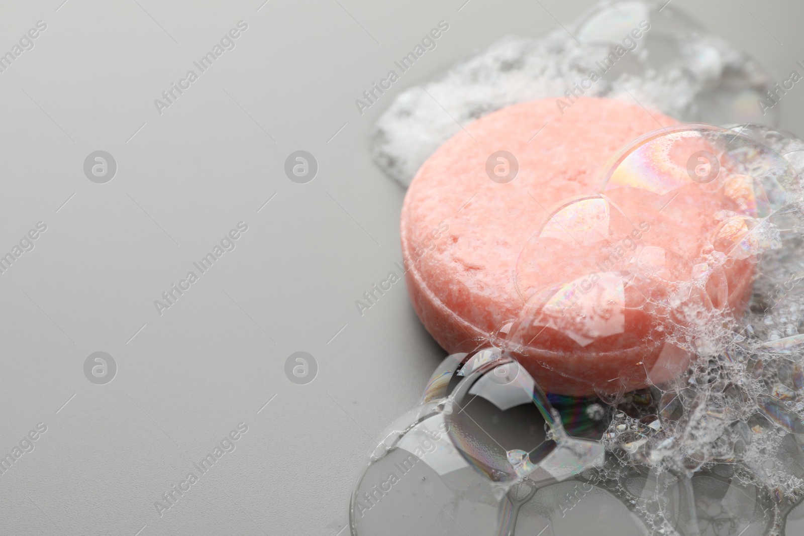 Photo of Soap bar with foam on grey background, closeup. Space for text