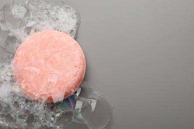 Photo of Soap bar with foam on grey background, top view. Space for text