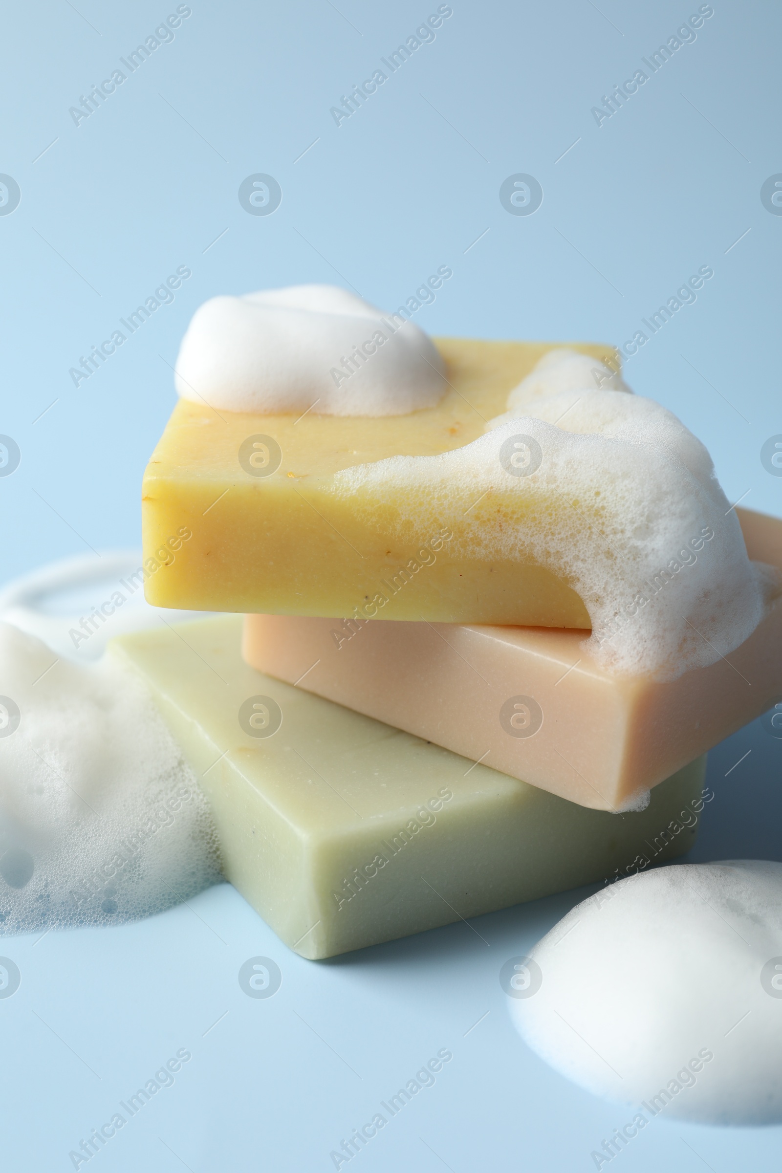 Photo of Soap bars with foam on light blue background