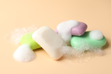 Photo of Soap bars with foam on beige background