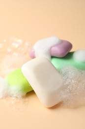 Photo of Soap bars with foam on beige background, closeup