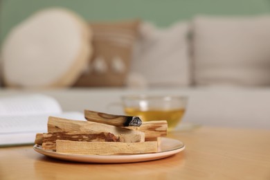 Photo of Palo santo sticks and burnt one on wooden table indoors, space for text