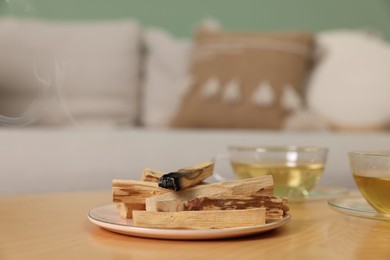 Photo of Palo santo sticks and burnt one on wooden table indoors, space for text