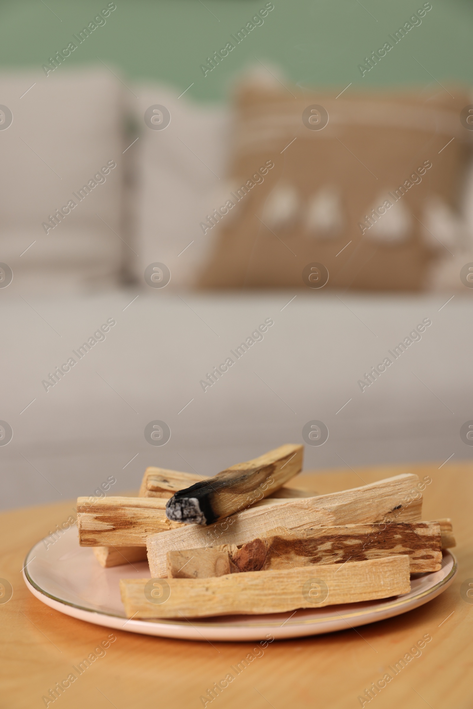 Photo of Palo santo sticks and burnt one on wooden table indoors, space for text