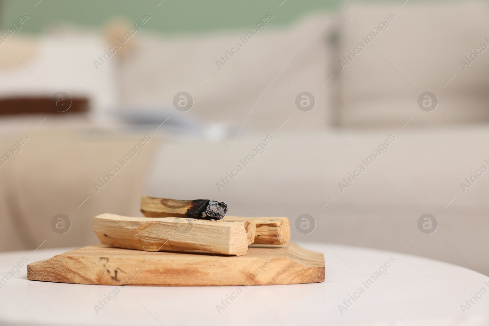 Photo of Palo santo sticks and burnt one on white table indoors, space for text