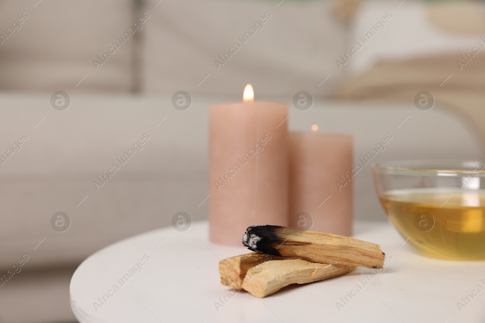 Photo of Palo santo sticks, burning candles and tea on white table indoors, space for text