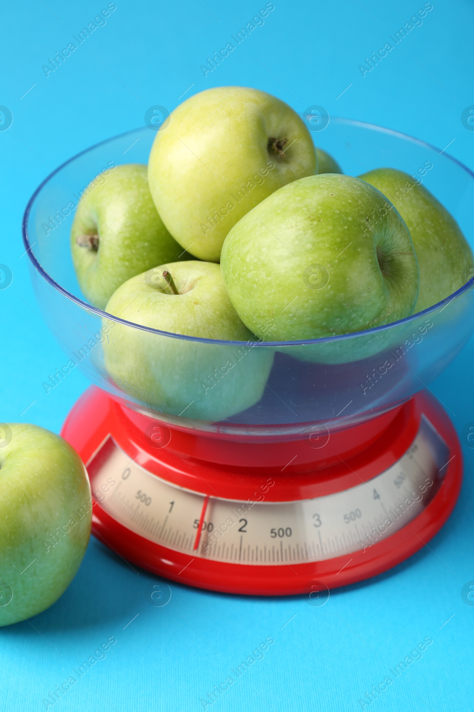 Photo of Kitchen scale with apples on light blue background, closeup