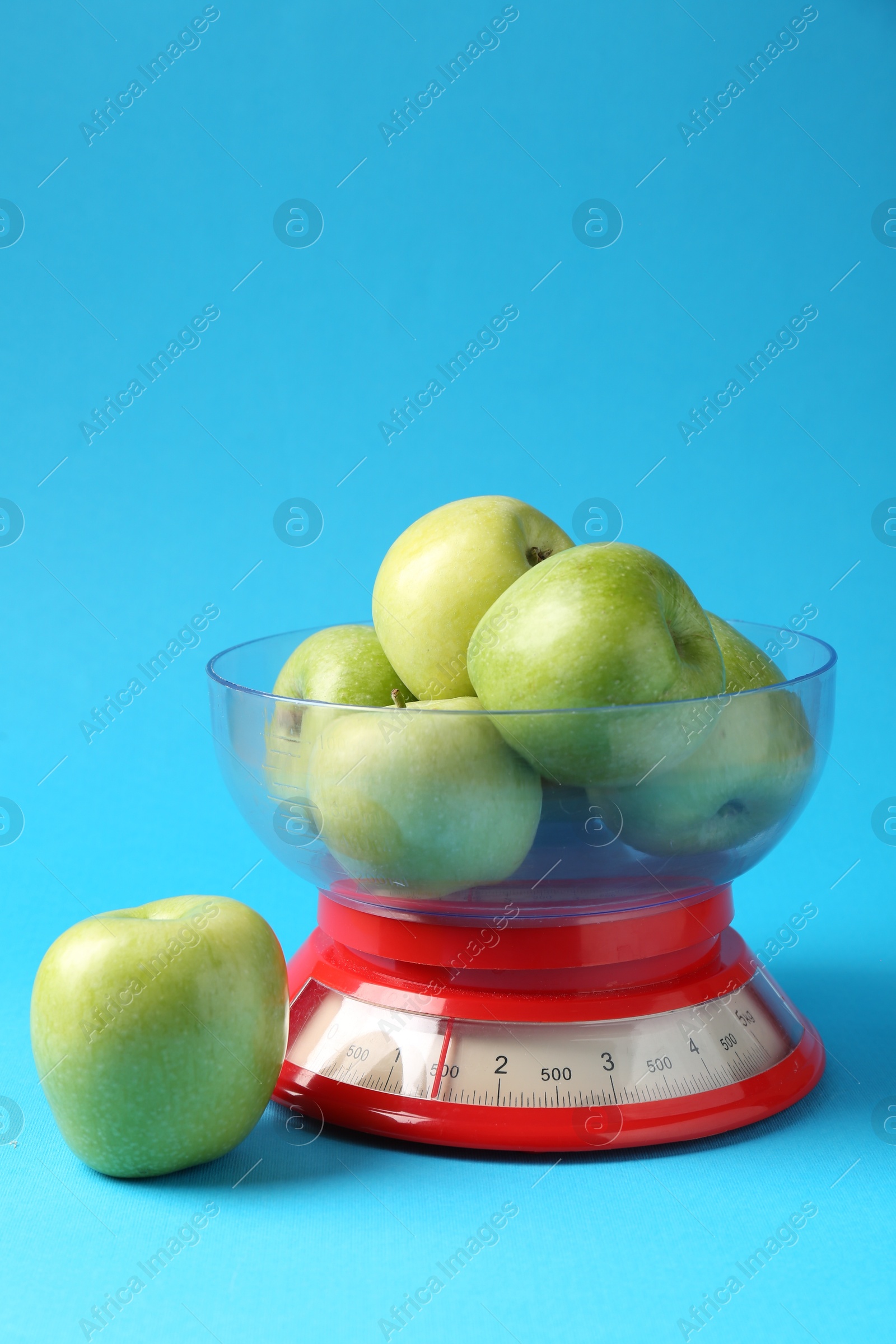 Photo of Kitchen scale with apples on light blue background