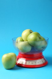 Photo of Kitchen scale with apples on light blue background