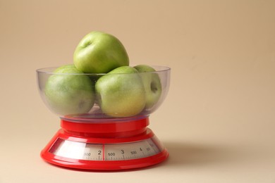 Photo of Kitchen scale with apples on beige background, closeup