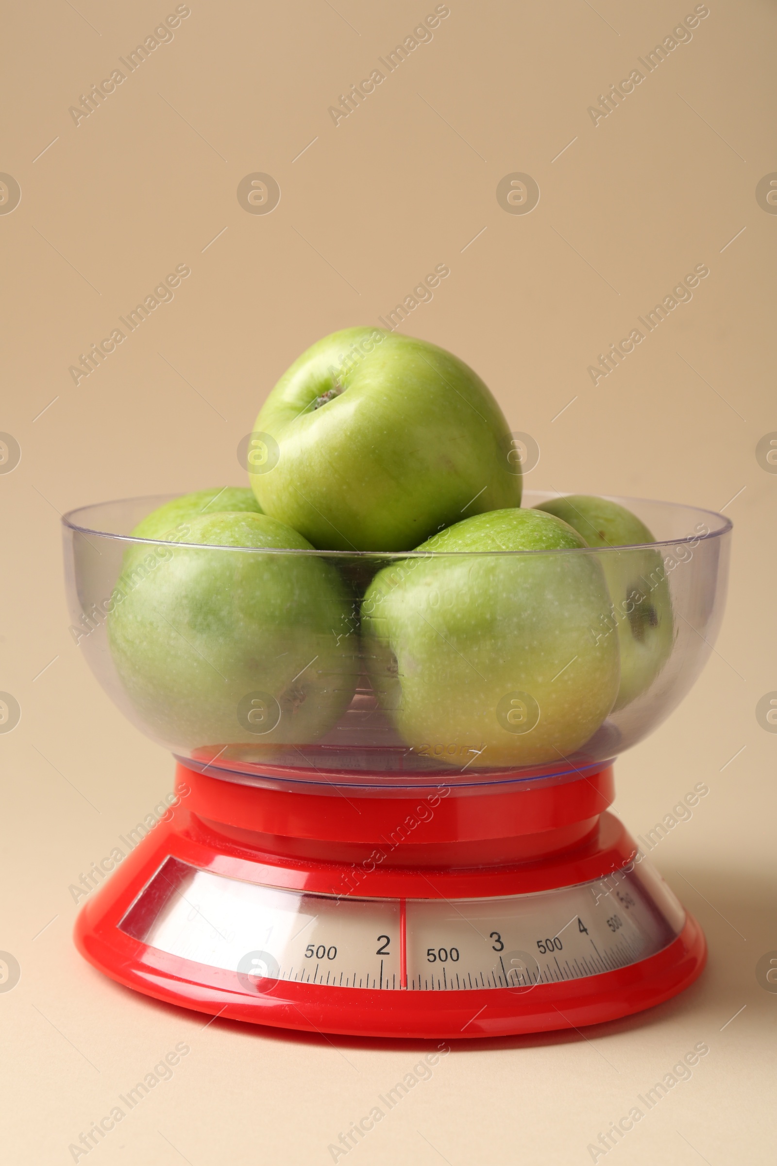 Photo of Kitchen scale with apples on beige background, closeup