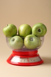 Photo of Kitchen scale with apples on beige background, closeup