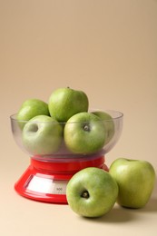 Photo of Kitchen scale with apples on beige background