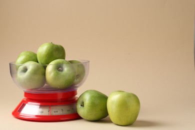 Photo of Kitchen scale with apples on beige background. Space for text