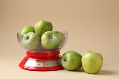 Photo of Kitchen scale with apples on beige background. Space for text