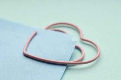 Photo of Paper notes attached with clip on light blue background, closeup