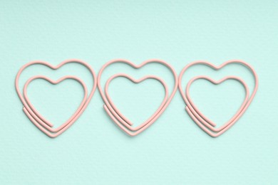 Photo of Heart shaped paper clips on light blue background, flat lay