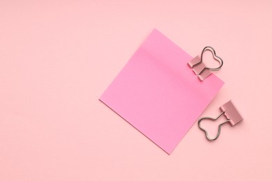 Photo of Heart shaped binder clips and blank paper note on pink background, flat lay. Space for text