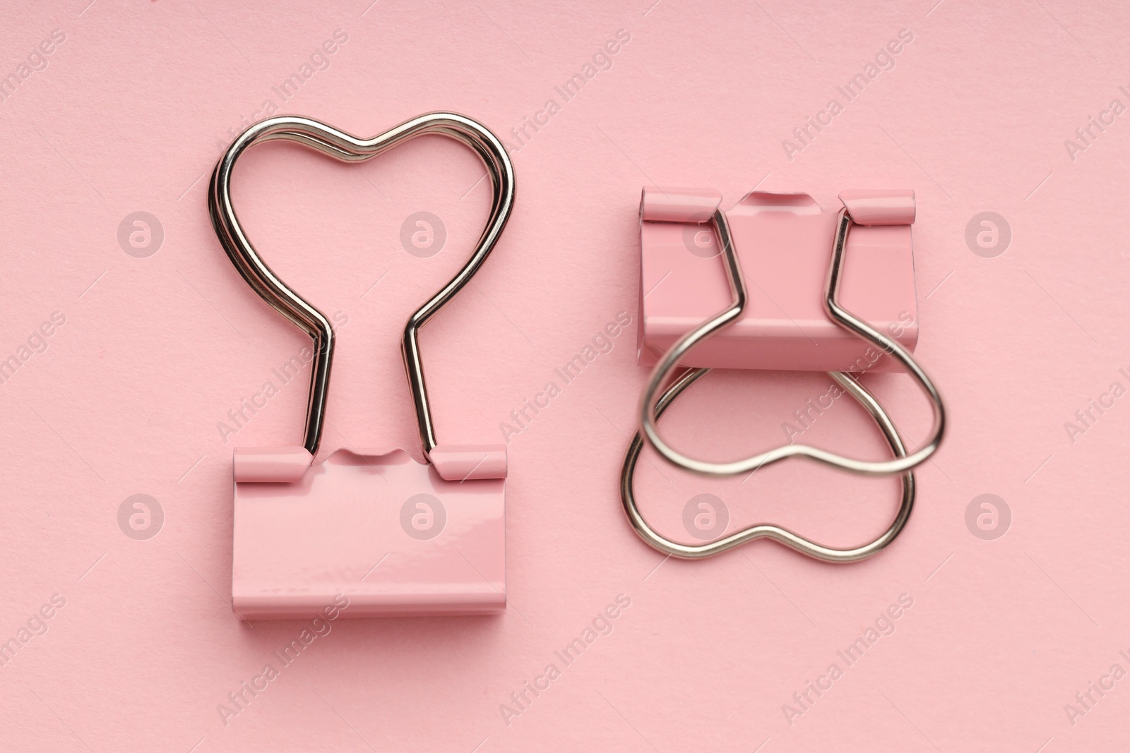 Photo of Heart shaped binder clips on pink background, flat lay