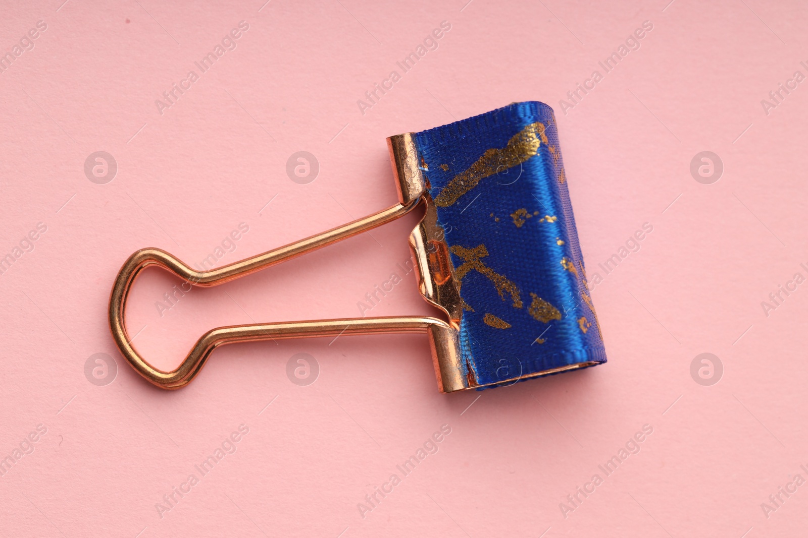 Photo of One binder clip on pink background, top view