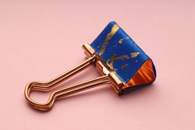 Photo of One binder clip on pink background, closeup