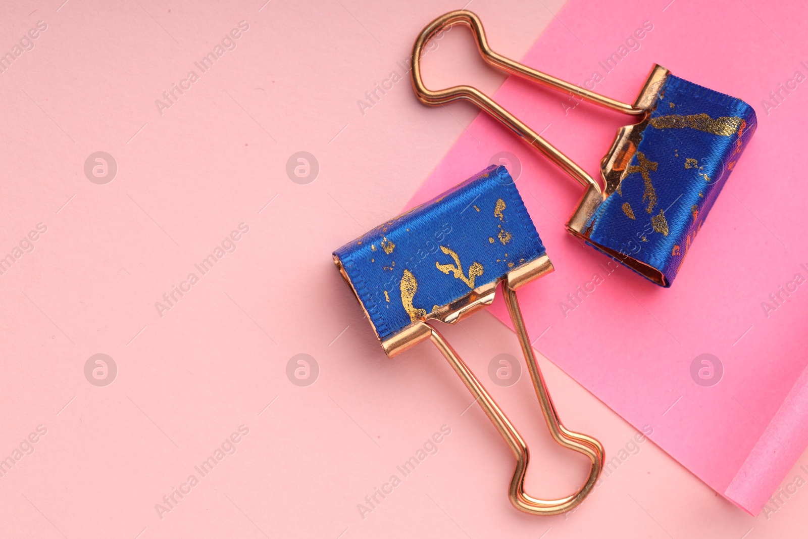 Photo of Binder clips and paper note on pink background, flat lay. Space for text