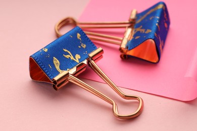 Photo of Binder clips and paper note on pink background, closeup