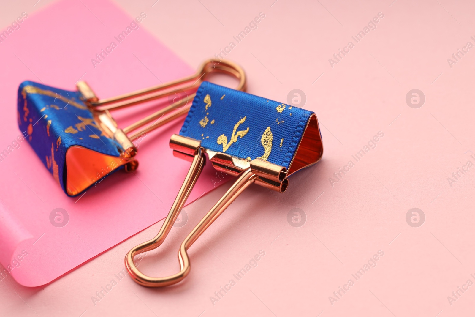 Photo of Binder clips and paper note on pink background, closeup. Space for text