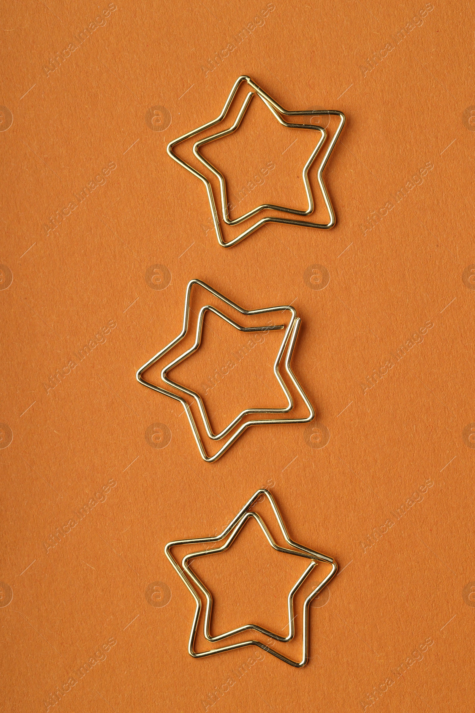 Photo of Star shaped paper clips on orange background, flat lay