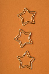 Photo of Star shaped paper clips on orange background, flat lay