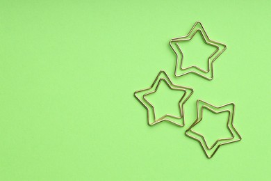 Photo of Star shaped paper clips on green background, flat lay. Space for text