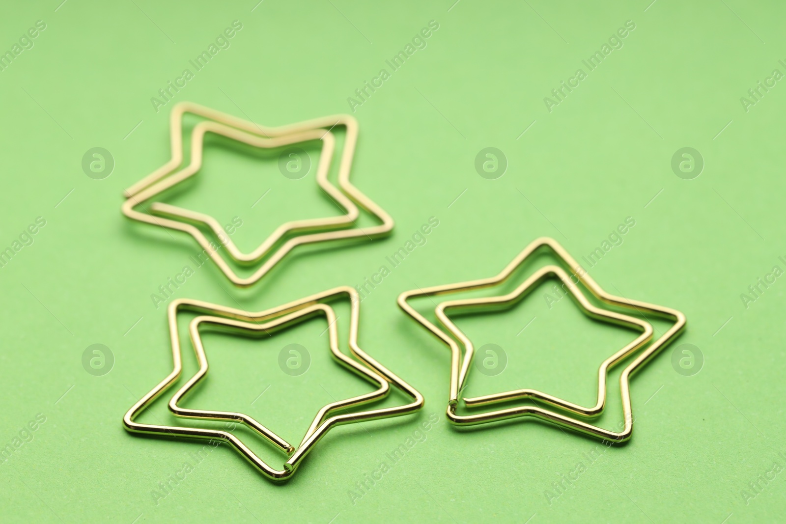 Photo of Star shaped paper clips on green background, closeup