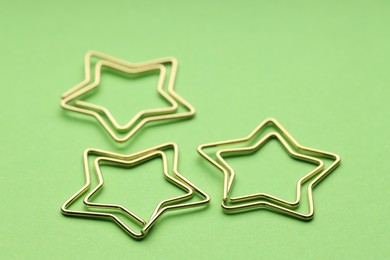 Photo of Star shaped paper clips on green background, closeup