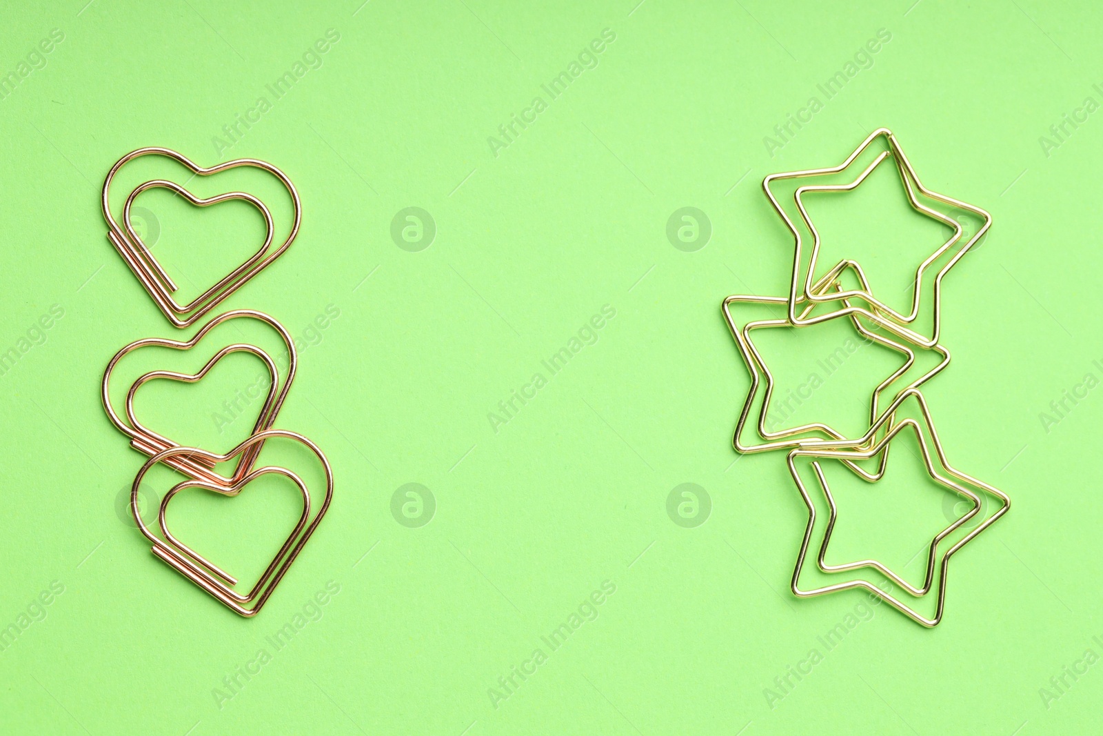 Photo of Different paper clips on green background, flat lay. Space for text