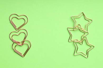 Photo of Different paper clips on green background, flat lay. Space for text