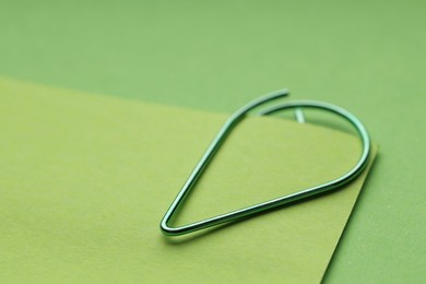 Photo of Paper note attached with clip on green background, closeup