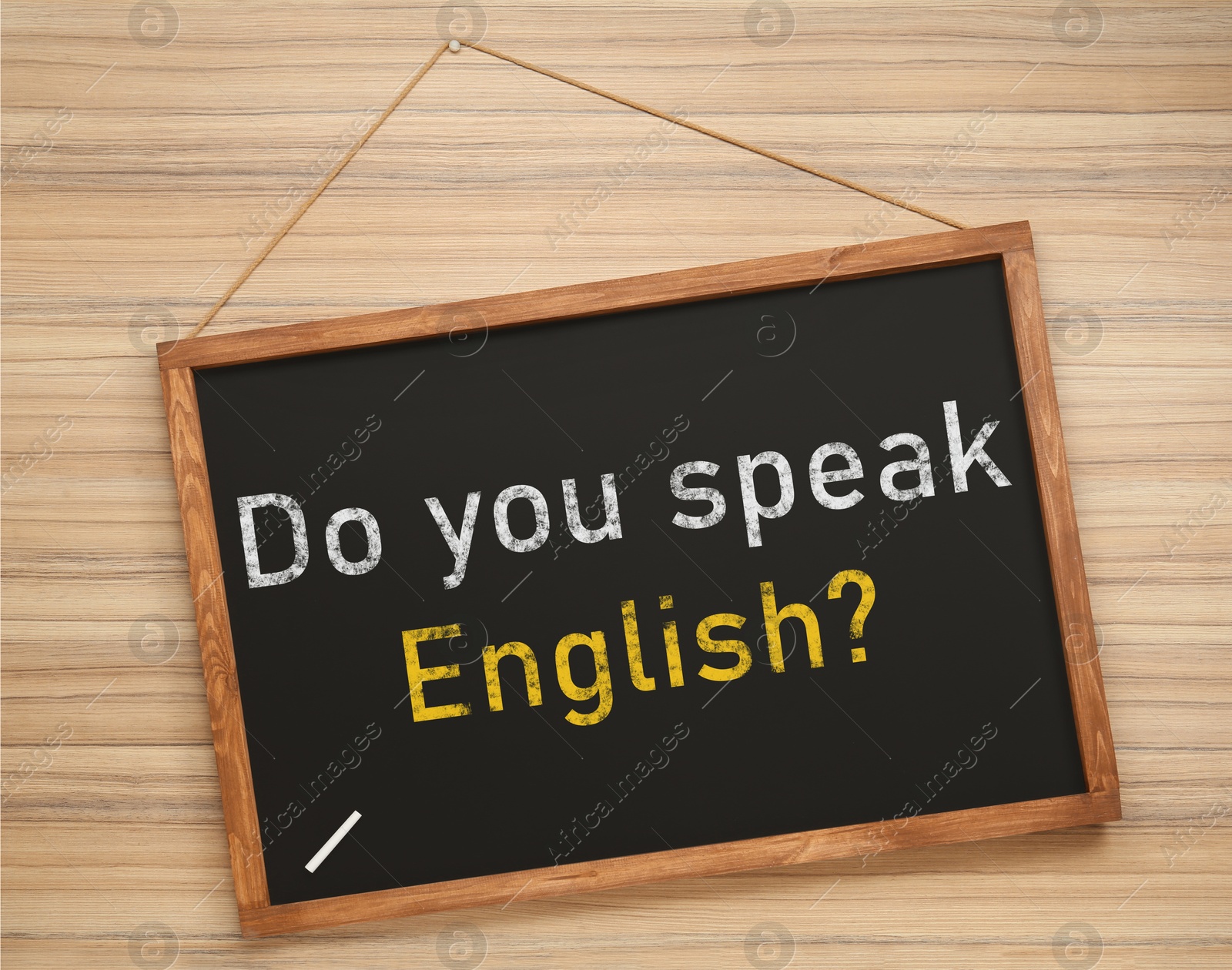 Image of Small black chalkboard with text Do You Speak English? on wooden background. Language course