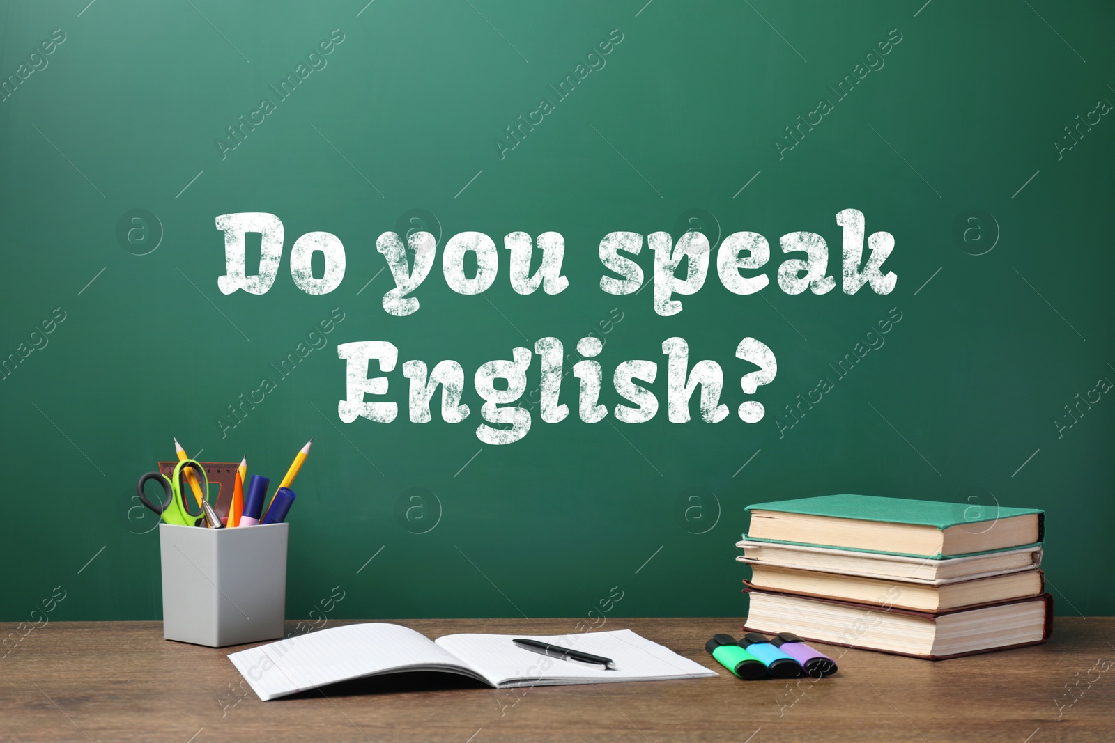 Image of Do You Speak English? text on green chalkboard and stationery on wooden table. Language course